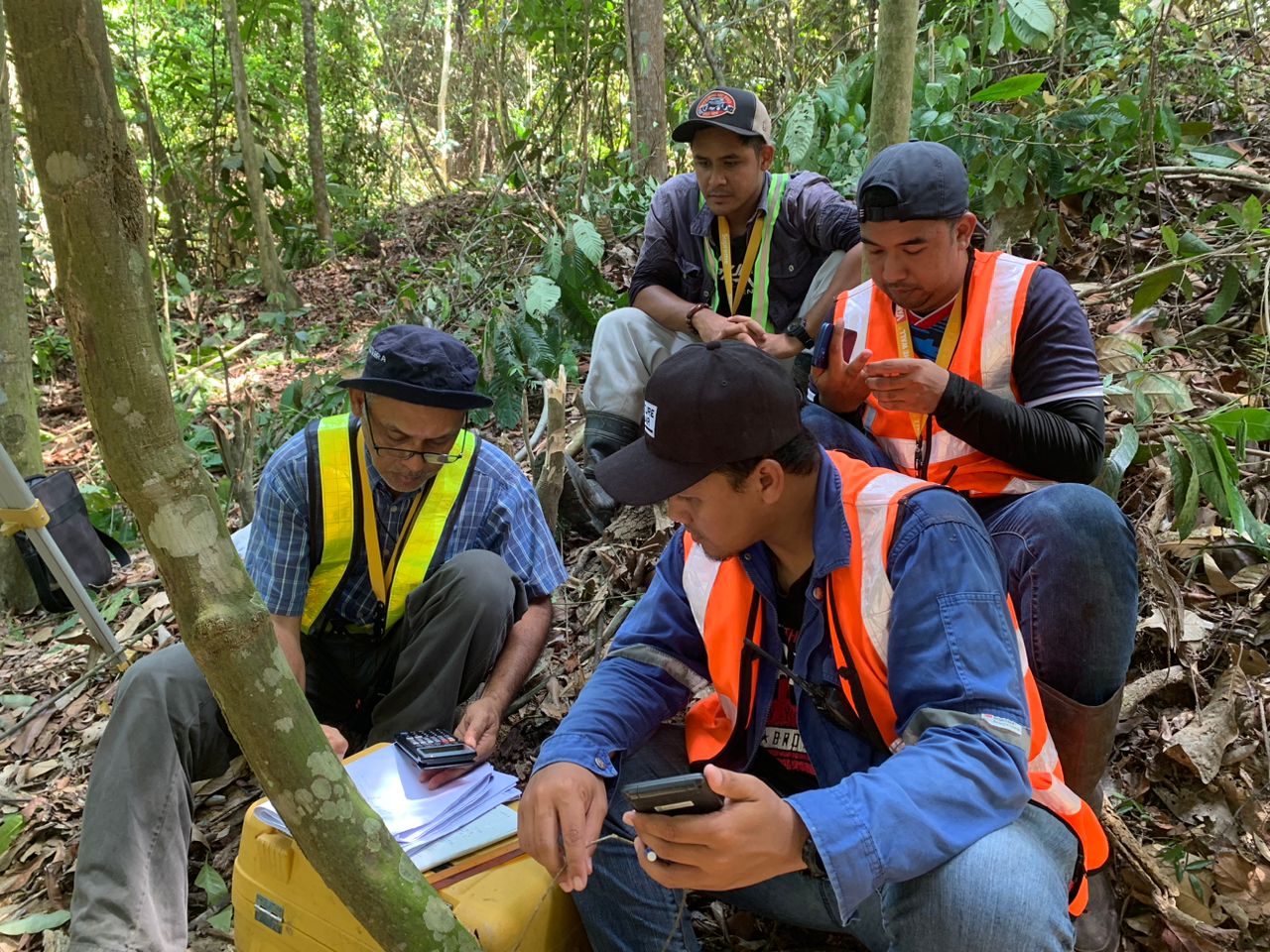 Survey team reviewing measurements in a wooded area